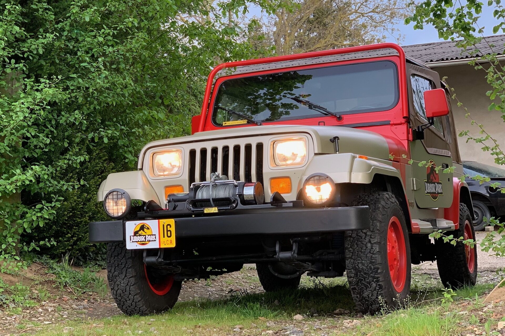 Ein Jurassic Park Jeep mit der Flottennummer 16 in einer Einfahrt zwischen Bäumen